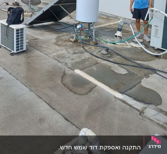 אדם ליד דוד שמש על גג עם ציוד